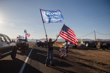 A woman waves a Trump and a US National flag as a caravan of cars from Kingman, Arizona drives past supporting President Trump, as they gather for a presidential debate watch party, in Golden Valley on October 22, 2020.