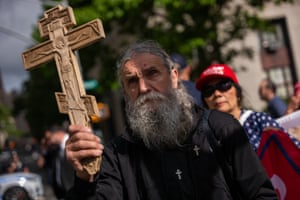 Supporters, including a man holding a large cross, watch as former president Donald Trump arrives at Manhattan Criminal Court on Thursday.