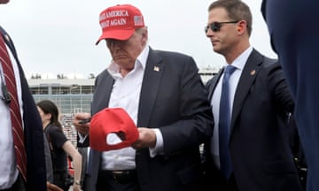Former President Donald Trump signs a hat for a fan as he attends the NASCAR Coca-Cola 600 auto race, Sunday, May 26, 2024, in Concord, N.C. It is the first time that a president or former president has attended a race at Charlotte Motor Speedway. (AP Photo/Chris Seward)