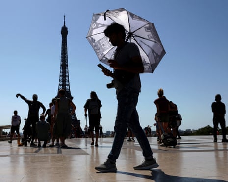 A tourist holding an umbrella to protect himself from the sun near the Eiffel Tower.