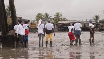 A group of people wearing wellies stand in the muddy San Antonia estuary