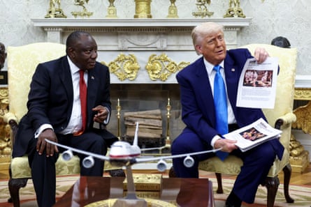 Cyril Ramaphosa looks at Donald Trump as he holds up print outs of alleged news articles.