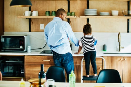 Young girl standing on stool in kitchen while helping father make dinner