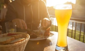 Unrecognizable young man having lunch and drinking beer in the pub