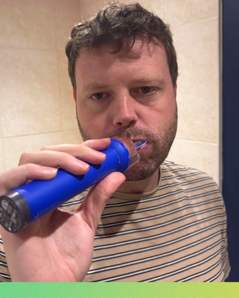 Writer Alan Martin using the Dyson CameraJet toothbrush in a bathroom.