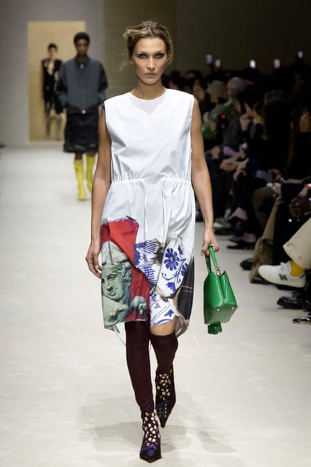 Bella Hadid walks the Prada runway in a white dress carrying a green handbag