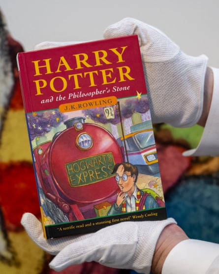 An art handler at Sotheby’s New Yorks holds up the first Harry Potter book