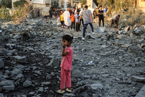 A Palestinian girl stands on rubble as she looks at the destruction in the al-Bureij camp in the central Gaza Strip.