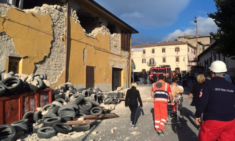 Rescuers and people walk along a road following an earthquake in Accumoli di Rieti, central Italy
