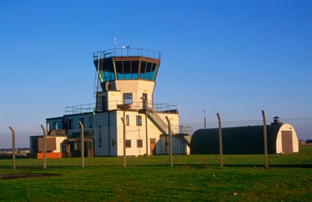 A white military-looking building with a control tower, surrounded by a fence