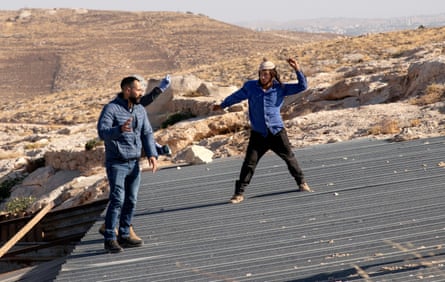 A settler throws a rock at Palestinians as they try to take down a sheep pen