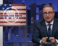 Man in suit and glasses speaks at desk, a graphic for the Republican party against an American flag on screen