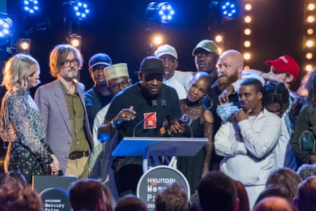 Skepta on stage after winning 2016 Mercury prize stood with other performers, Lauren Laverne and Jarvis Cocker,