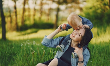 beautiful long-haired young mother in the summer sunshine park are sitting and playing with little cute sons