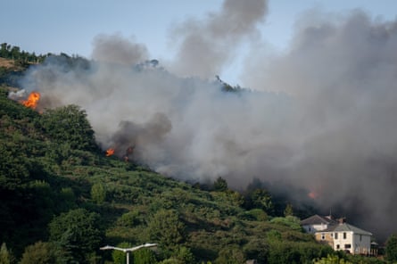 Fire on a hillside above a house.