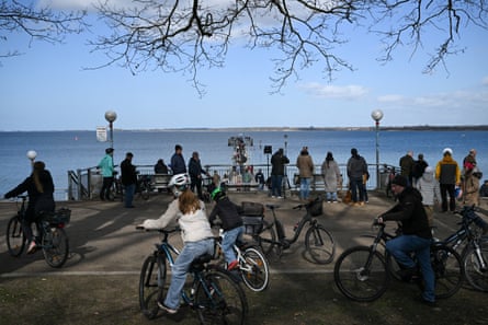 People on foot or on bikes look out from on a bridge at Wismar Bay on Sunday where the whale was stuck in shallow waters.