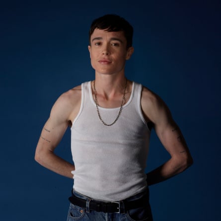 Elliot Page wearing a white vest and chain, against a blue background