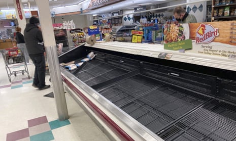 A shopper browses through the few packages of chicken left in a nearly empty refrigerated case in Denver on 11 March. 