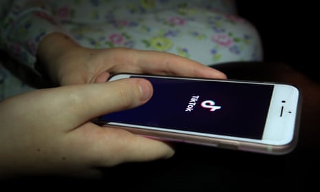 A young person using the TikTok app on a smartphone.