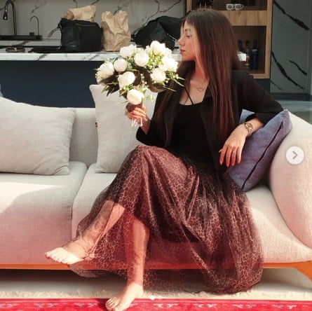 Romina sitting on a sofa smelling a bouquet of white flowers