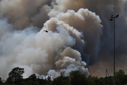 A huge smoky cloud with a helicopter flying in front of it.