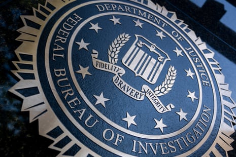 A close-up of the FBI seal, reading 'Department of Justice Federal Bureau of Investigation'.