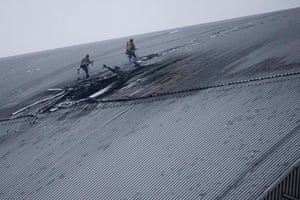 Two workers appear to be abseiling down a large grey structure