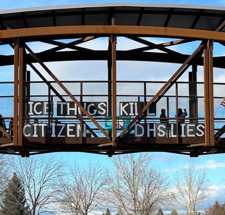 people hold signs while stand on freeway overpass