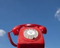 Red old-fashioned telephone with the words 'contact us' in the centre of the dialling pad, against a blue sky