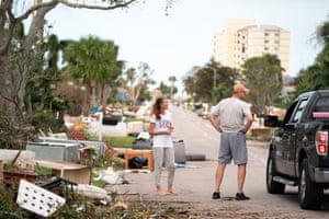 people talk to a driver on a street littered with debris