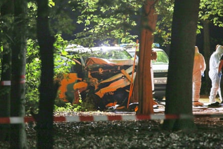 Forensic investigators collect evidence from a white van that has crashed into a tree