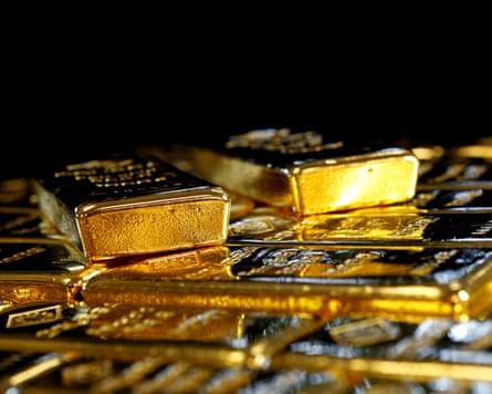 A pile of gold bars shining against a dark background