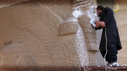 An IS militant destroys a 7th-century statue of a lamassu, an Assyrian diety, with a jackhammer in Mosul Museum, Iraq.