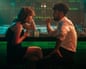 A young heterosexual couple having a heated argument sitting on bar stools by the bar in a nightclub.