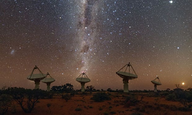 The Askap radio telescope infrastructure in a desert beneath a starry night sky