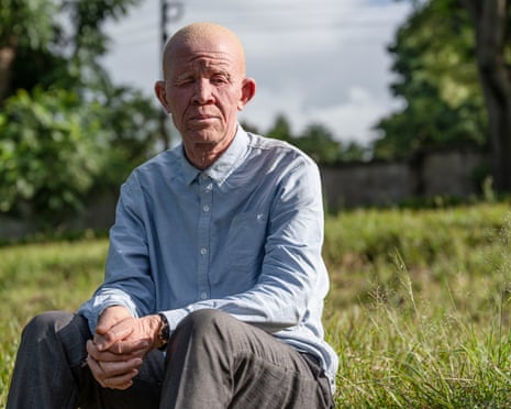 A man in a blue shirt sits in a field