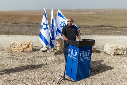 Gadi Eisenkot speaks at a podium outdoors, with Israeli flags behind him