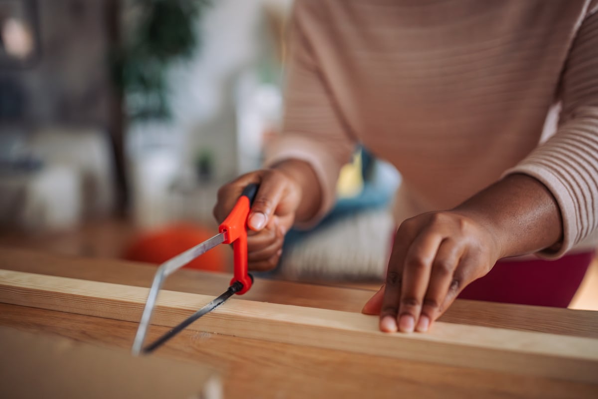 someone chops a piece of wood with a handsaw.