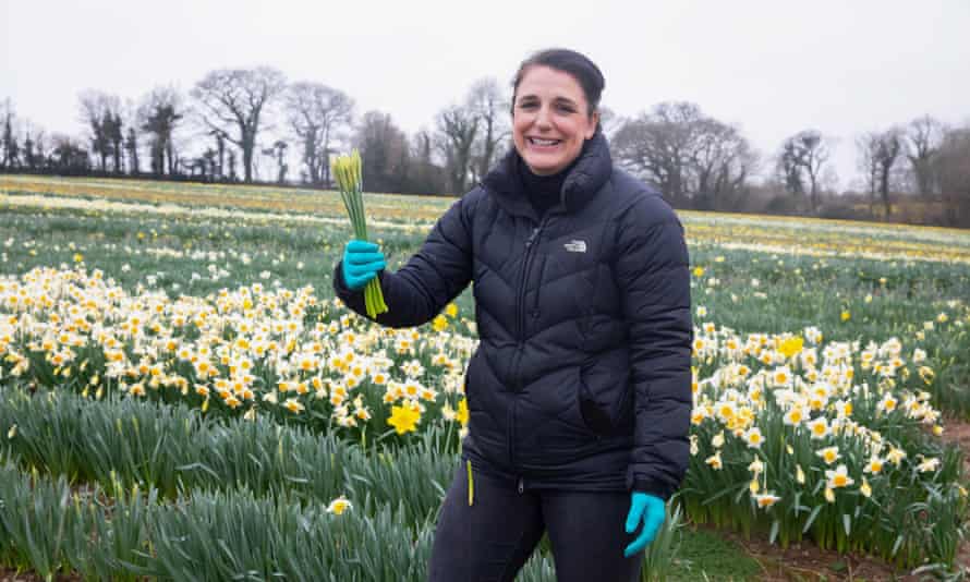 Rachel Stevenson holds up a small clutch of daffodils, smiling.