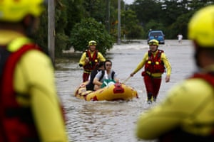 Queensland Fire and Emergency Services crew members use an inflatable boat to pull residents through flood waters