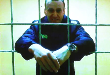 Alexei Navalny standing in a cell with his hands crossed between the bars