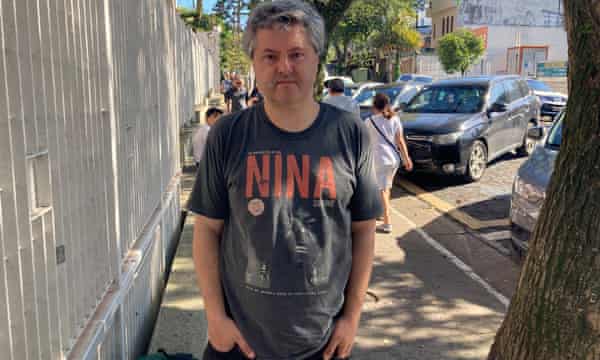 The Brazilian author Ricardo Lísias, wearing a Nina Simone T-shirt, stands on a pavement on a sunny day