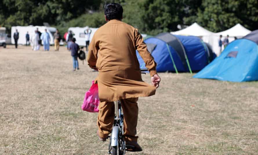 An attendee of the UK’s largest Muslim convention, Jalsa Salana, rides a bicycle through a field of tents