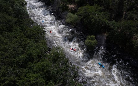 Aerial view of river between forests and bright kayaks on it.