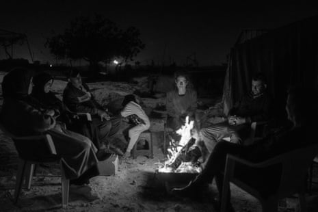 An activist sits with the family at night at their property