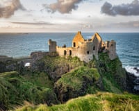 A ruined castle on a grassy rugged clifftop overlooking the sea