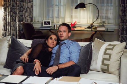 Meghan, as Rachel Zane, with Patrick J Adams, as Michael Ross, sitting on a sofa in a living room