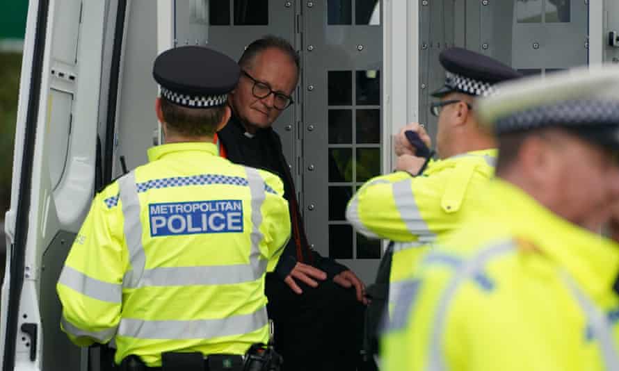 Police officers put an Insulate Britain protester wearing a dog collar into the back of a van after he was detained while occupying a roundabout leading from the M25 motorway to Heathrow on Monday.