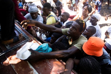 Crowd of people reach up into a pickup truck.