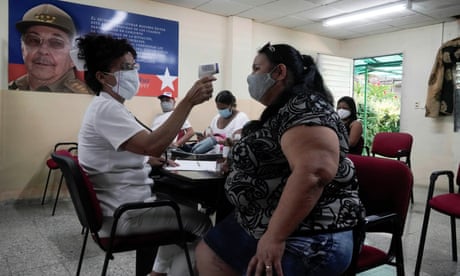 Propagation de la maladie à coronavirus (COVID-19) à Cuba<br>Une femme fait vérifier sa température après avoir reçu une dose du vaccin Abdala dans un centre de vaccination à côté d’une image de l’ancien président et premier secrétaire du Parti communiste cubain Raul Castro au milieu des inquiétudes concernant la propagation de la maladie à coronavirus (COVID-19), à La Havane, Cuba, le 2 août 2021. Photo prise le 2 août 2021. REUTERS/Alexandre Meneghini